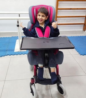 A young boy in a chair adapted to his disability.