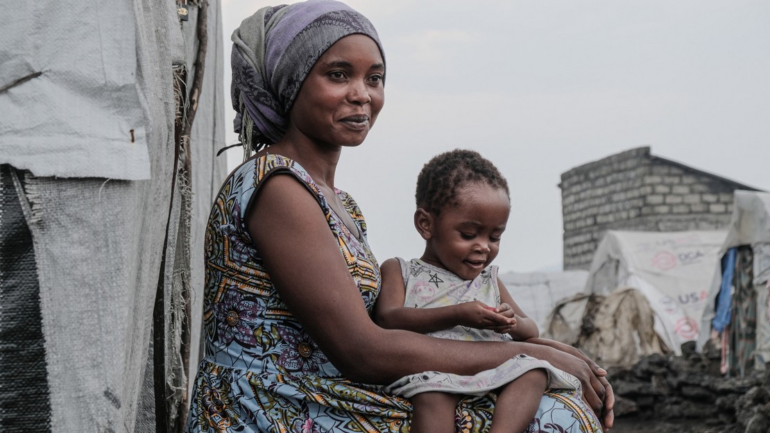 A woman with her daughter on her knees.; }}