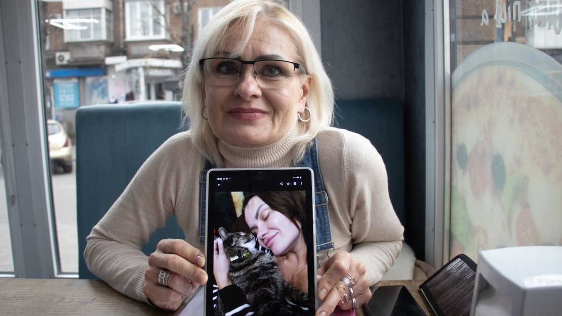 Elena, 53 ans et sa fille Yevgenia, 34 ans, ont survécu toutes les deux à des bombardements, dans l’Est de l’Ukraine.Elle pose dans un café en montrant une photo de sa fille avec son chat ; }}