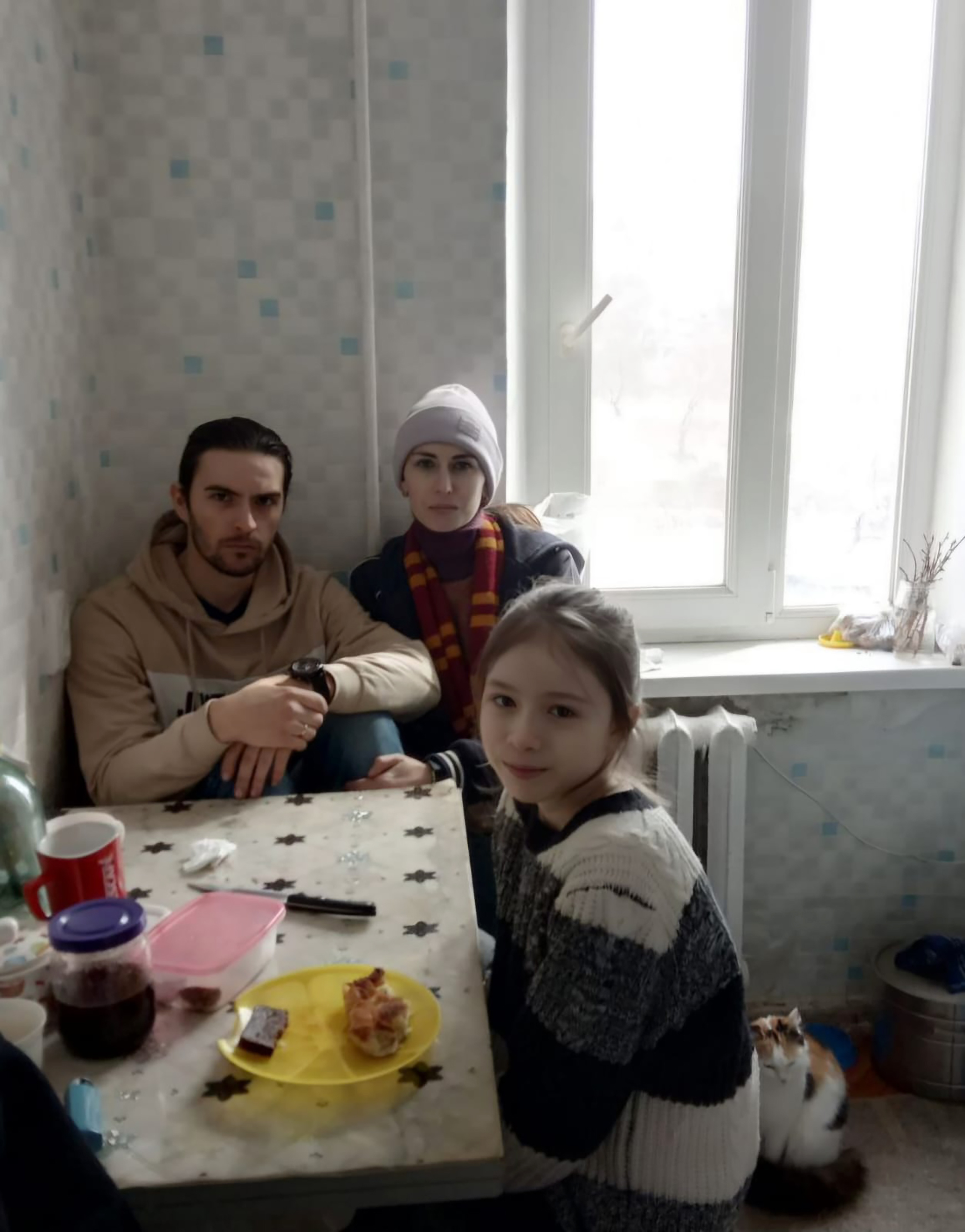 Antonina and her family posing in their kitchen, at the table, wearing winter clothes, during the siege of their city