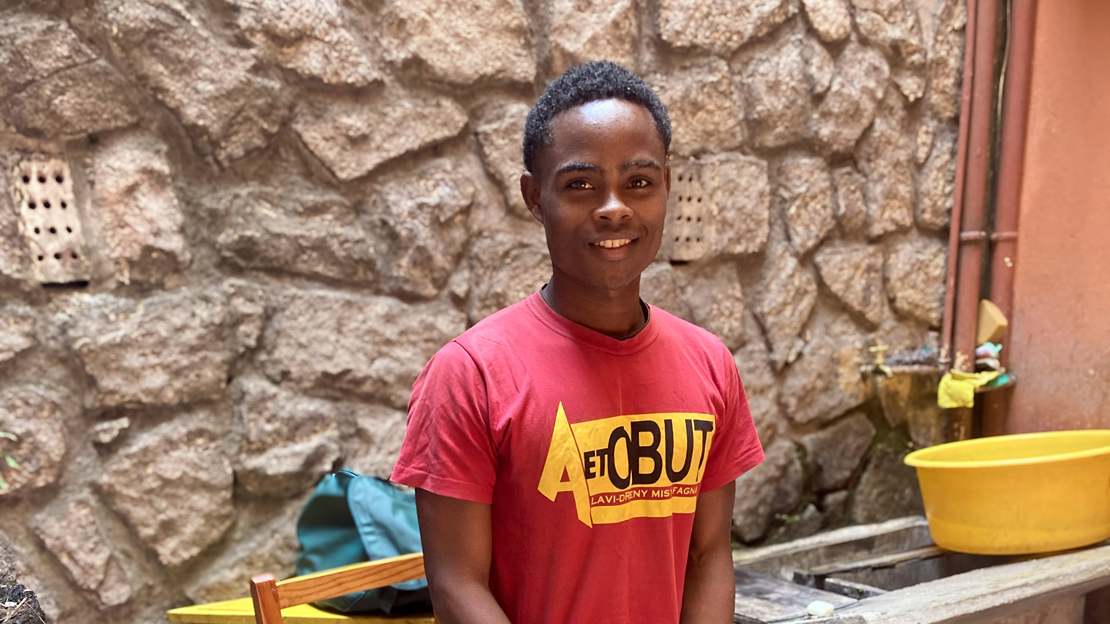 A young man, who received of a refurbished prosthesis, stands in the HI Madagascar office.; }}