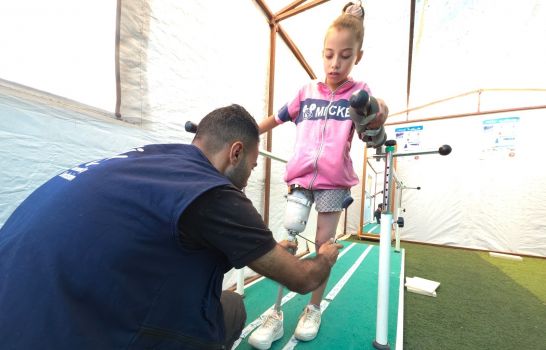 Malak is pictured at the HI prosthetics and orthotics centre during a physiotherapy session. She is learning how to walk with her artificial leg; }}