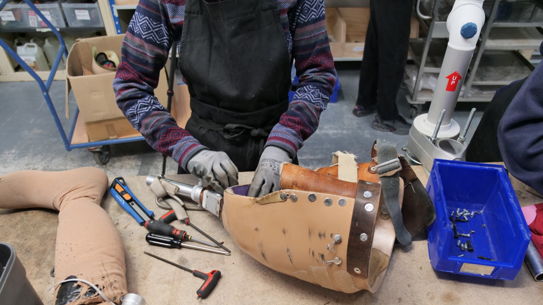 A Liimba project volunteer is dismantling a prosthesis to recover its components.; }}