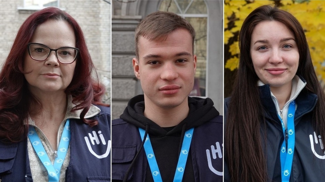 Three side-by-side portraits show members of the humanitarian organization HI. On the left, a woman with red hair and glasses wears a blue vest with the HI logo and a badge around her neck. In the center, a young man with short hair wears a black hoodie under his HI vest. On the right, a smiling young woman with long brown hair wears an HI jacket. ; }}